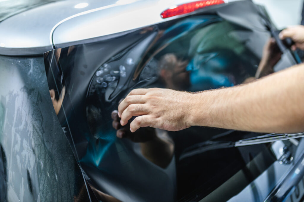 Car tinting - Worker applying tinting foil on car window.